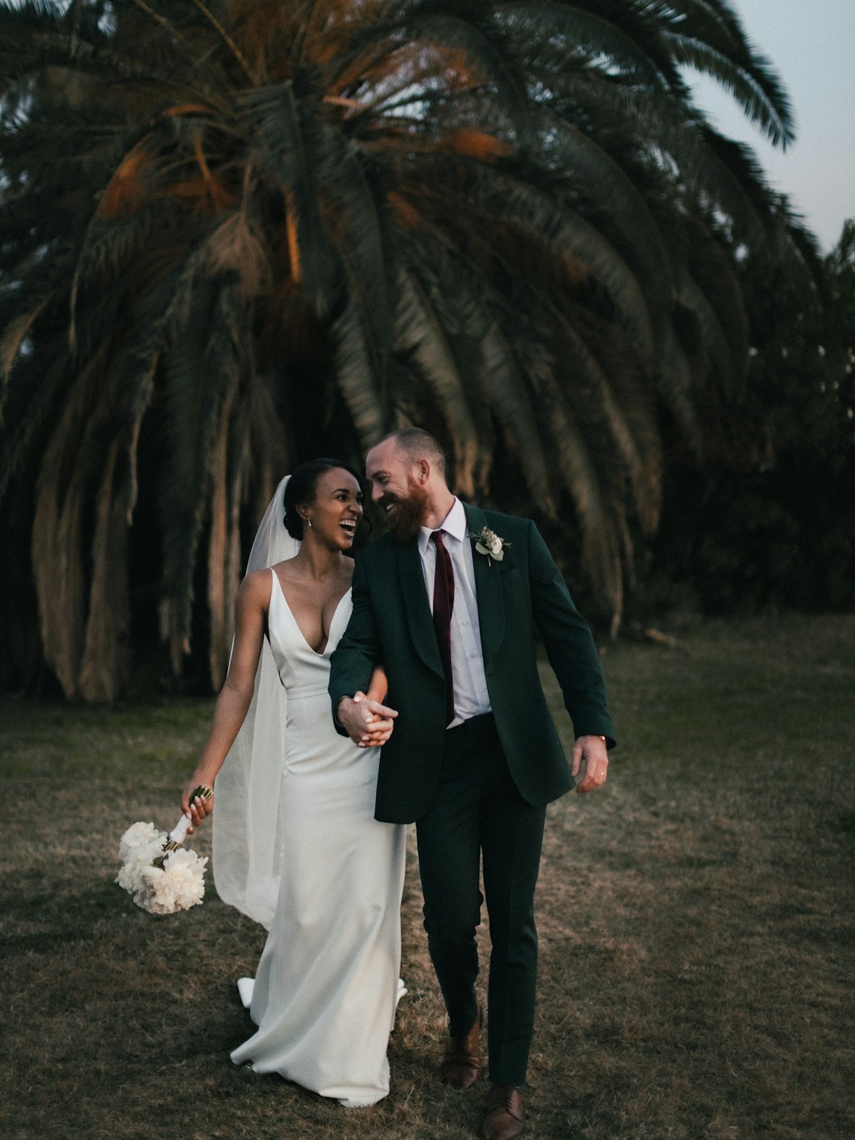 Pareja de novios caminando en un jardín con palmeras